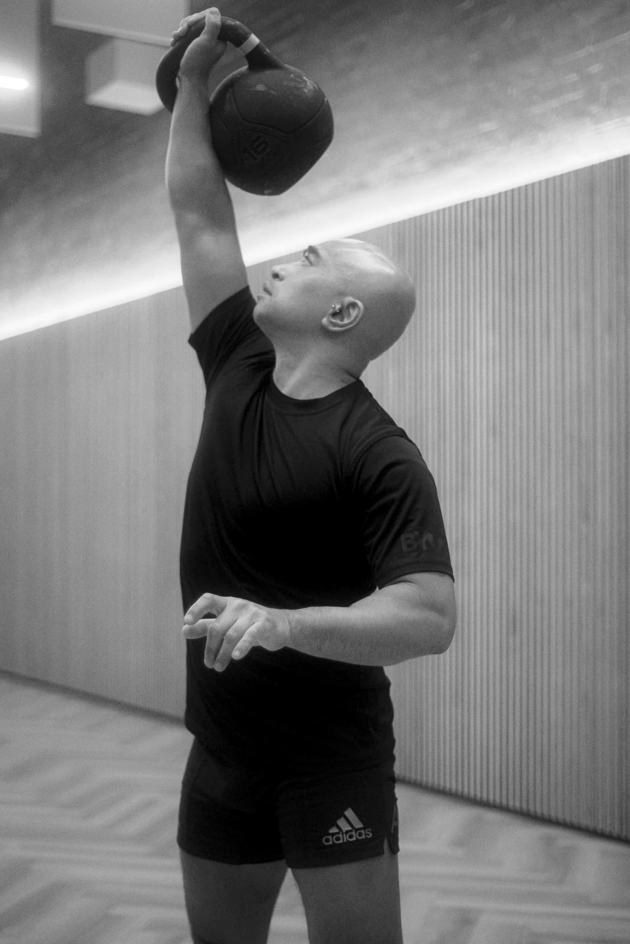 Seb pressing a kettlebell overhead in a Berlin training studio